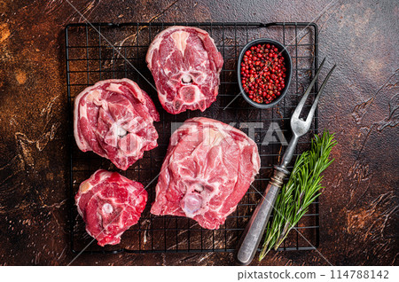 Fresh Raw lamb neck meat slices, mutton meat on a rack with herbs. Dark background. Top view 114788142