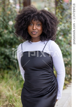 Black Woman in Black Dress and White Top Posing Outdoors 114789418