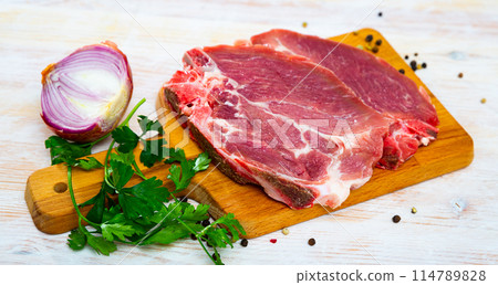 Sliced raw pork chop with parsley and onion Sliced raw pork chop with parsley and onion 114789828