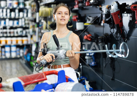 Young female buyer chooses mixer for building mixtures in hardware store 114789878