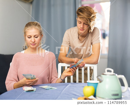 Woman counting family budget and giving pocket money to teenage son 114789955