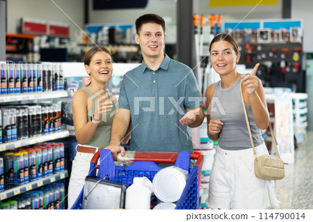 Positive family discussing purchases while standing with cart in hardware store 114790014