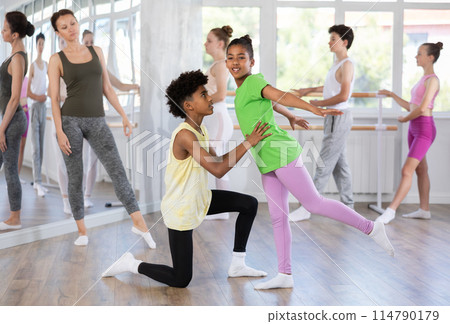 Teenage boy and girl doing together arabesque position of ballet during choreography classes Teenage boy and girl doing together arabesque position of ballet during choreography classes 114790179