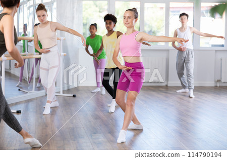 Teenage girl practicing basic ballet moves at group class 114790194
