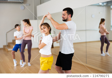Teen girl practicing boogie-woogie in pair with father in dance studio Teen girl practicing boogie-woogie in pair with father in dance studio 114790271