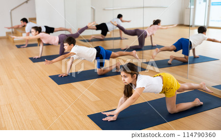 Tween girl performing Balancing Table pose during family yoga class 114790360