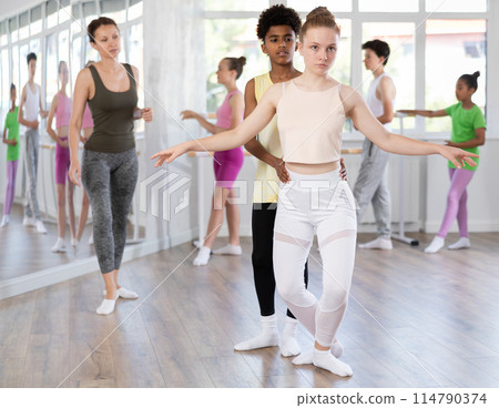 Teenage girl and boy practicing plie position of ballet in dance studio Teenage girl and boy practicing plie position of ballet in dance studio 114790374