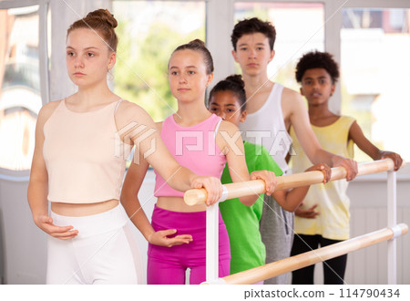 Teenage girl practicing position holding by ballet barre during workout session Teenage girl practicing position holding by ballet barre during workout session 114790434