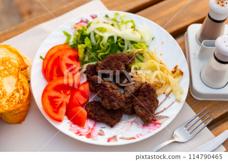 Turkish kofte, grilled veal meatballs with vegetables and bread 114790465