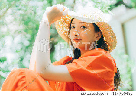 Young woman putting on a straw hat 114790485