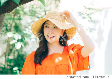 Young woman putting on a straw hat Young woman putting on a straw hat 114790493