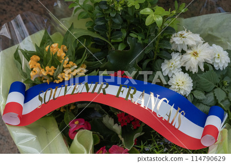 Flower wreath and ribbon at American cemetery monument at Normandy area. WWII memorial. Lines of grave stones with american flag. High quality photo 114790629