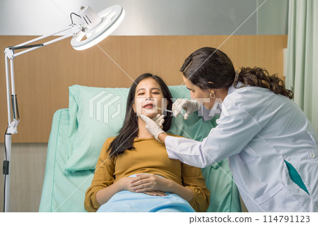 Doctor in white gown and protective glove giving female patient medical injection in lip. Atmosphere at cosmetic surgery department in hospital clinic. 114791123