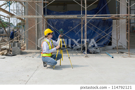 A construction worker is using a laser gauge to capture the setting of masonry, plastering and wall work at a building site. A construction worker is using a laser gauge to capture the setting of masonry, plastering and wall work at a building site. 114792121
