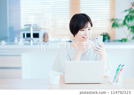 A housewife working remotely in the living room. A housewife working remotely in the living room. 114792523