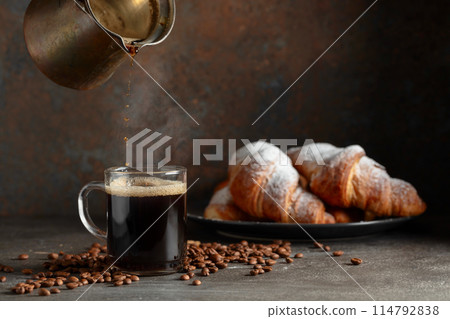 Croissants and black coffee on a kitchen table. 114792838