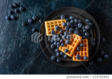 Belgian waffles with blueberries on a black plate. Belgian waffles with blueberries on a black plate. 114792842