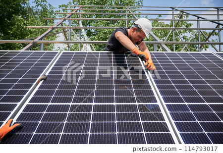 Workers installing solar panel on metal beams at sunny daytime. Renewable and ecological energy. Idea of environment safe. Modern technology and innovation. European man wearing workwear and helmets Workers installing solar panel on metal beams at sunny daytime. Renewable and ecological energy. Idea of environment safe. Modern technology and innovation. European man wearing workwear and helmets 114793017