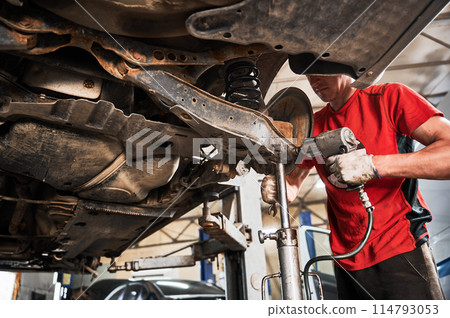 Close up of worker, repairman wearing dirty gloves, repairing, fixing car. Hardworking, strong man working in garage, auto, servicing center. Concept of repairing automobiles. Close up of worker, repairman wearing dirty gloves, repairing, fixing car. Hardworking, strong man working in garage, auto, servicing center. Concept of repairing automobiles. 114793053