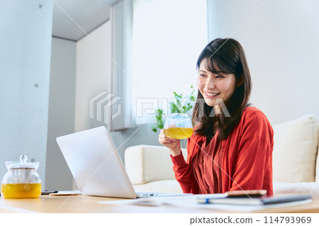 一名女士在休息日在客廳裡用筆記型電腦參加線上課程,以重新學習和重新掌握技能。 一名女士在休息日在客廳裡用筆記型電腦參加線上課程,以重新學習和重新掌握技能。 114793969