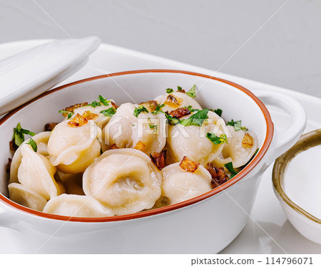 Delectable dumplings in ceramic pot on white plate Delectable dumplings in ceramic pot on white plate 114796071