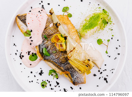 Gourmet pan-seared fish fillet with sauce and garnishes 114796097