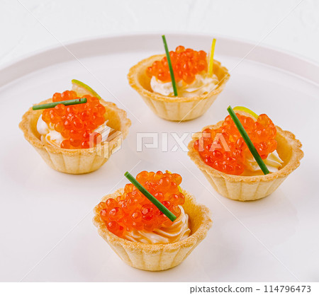 Elegant tartlets with salmon caviar on white plate 114796473