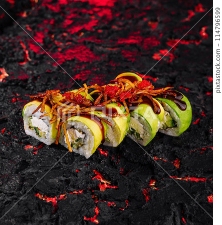 Spicy avocado sushi roll on lava-inspired surface Spicy avocado sushi roll on lava-inspired surface 114796599