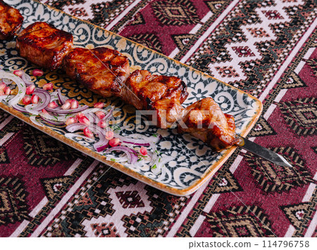Traditional grilled meat skewers on ornate plate Traditional grilled meat skewers on ornate plate 114796758