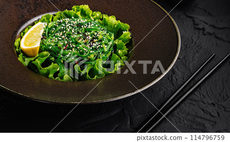 Fresh green seaweed salad with sesame seeds on dark plate 114796759