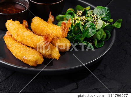 Crispy fried shrimp with dips and salad on dark plate 114796977