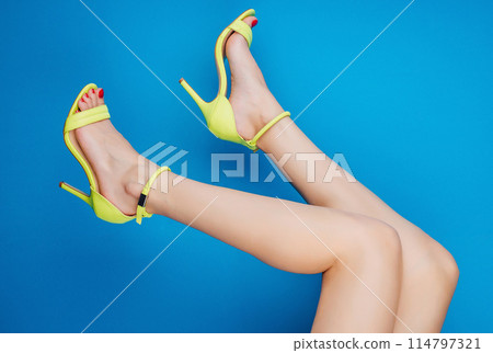 Fashionable legs in yellow high heels against blue background 114797321