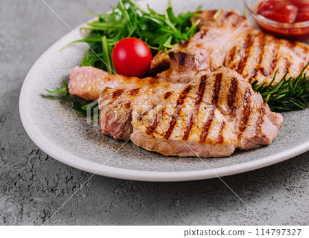 Grilled pork chops on ceramic plate with herbs 114797327