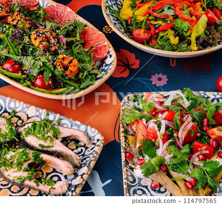 Colorful assortment of mediterranean dishes on patterned tablecloth 114797565