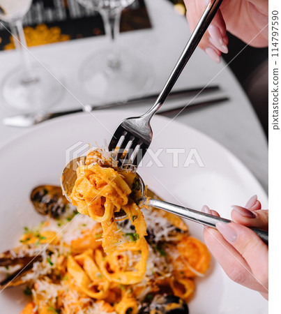 Enjoying seafood pasta at elegant dining table Enjoying seafood pasta at elegant dining table 114797590