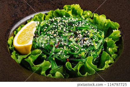 Fresh green seaweed salad with sesame seeds on dark plate 114797725