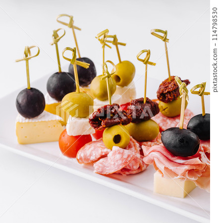 Gourmet appetizer selection on a white platter against a clean backdrop 114798530