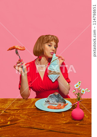 Chic Seafood Dining. Elegant young woman in re dress eating seafood, fish and shrimps against pink background. 114798651