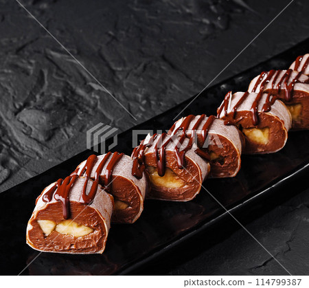 Chocolate drizzled profiteroles on dark plate 114799387
