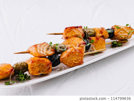 Gourmet grilled chicken skewers on white plate 114799636