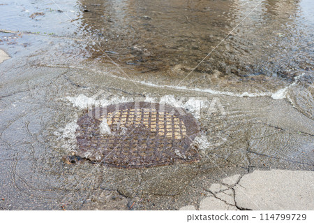 Water fountain pours out from sewer hatch, breakthrough sewerage system, accident of water supply 114799729