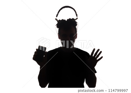 Silhouette of a young man with a smartphone with headphones Silhouette of a young man with a smartphone with headphones 114799997