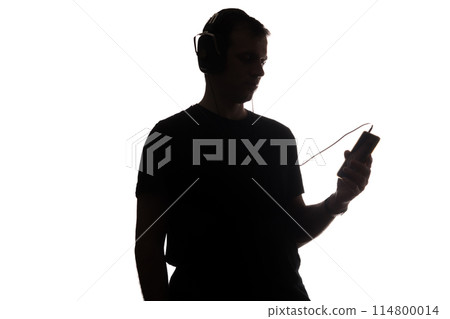 Silhouette of a young man with a smartphone with headphones 114800014
