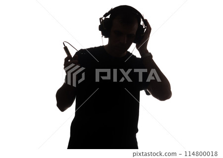 Silhouette of a young man with a smartphone with headphones 114800018