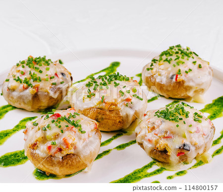 Gourmet stuffed mushrooms on plate with pesto drizzle 114800157