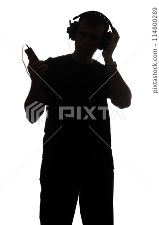 Silhouette of a young man with a smartphone with headphones Silhouette of a young man with a smartphone with headphones 114800289