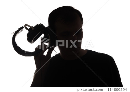 Silhouette of a young man with a smartphone with headphones Silhouette of a young man with a smartphone with headphones 114800294