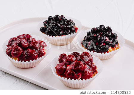 Assorted berry tartlets on white plate 114800523