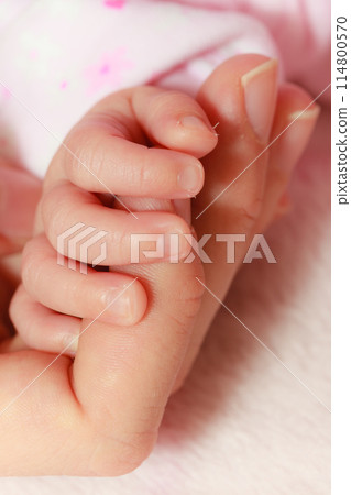 Baby sleeping in blanket holding mother hand Baby sleeping in blanket holding mother hand 114800570