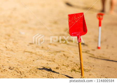 Two red toy shovels in sand on beach Two red toy shovels in sand on beach 114800584